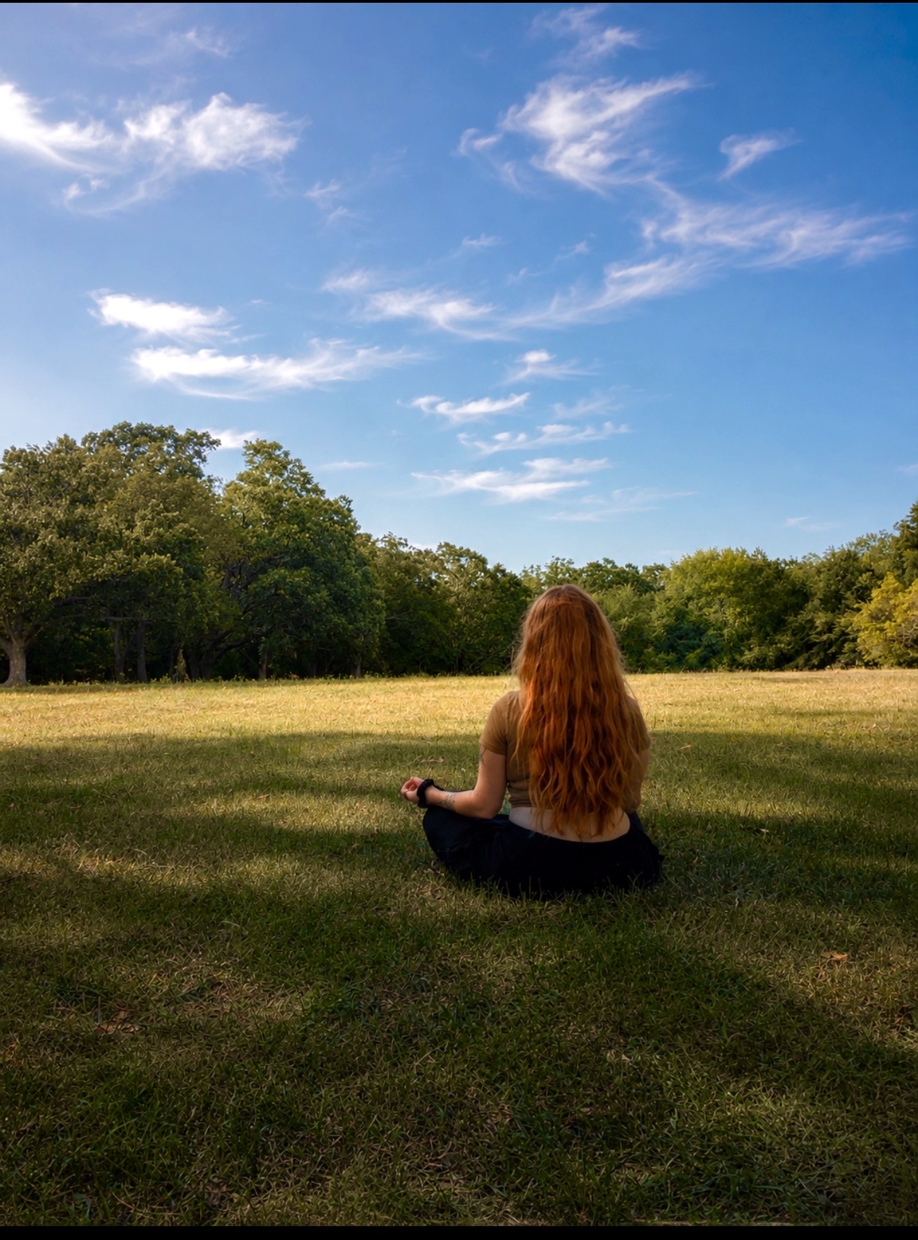 Liz sitting in meditation outdoors beneath an open sky