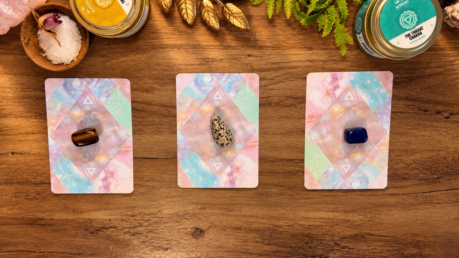 Three tarot cards with crystals on a wooden table